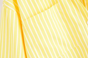 Detail of chest pocket stitching on yellow and white vertical striped V-neck shirt