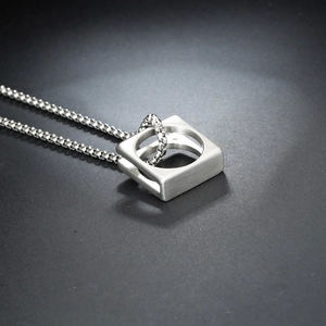 Silver square interlocking circle pendant with box chain on dark textured surface