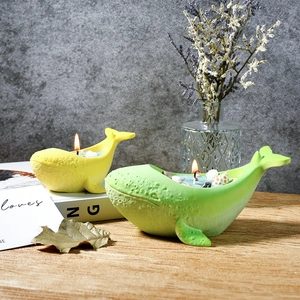 Macro shot of whale-shaped scented candles in green and yellow with seashells on top