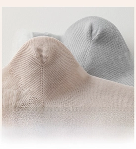 Close-up of reinforced heel detail on thin beige and grey socks with cotton texture