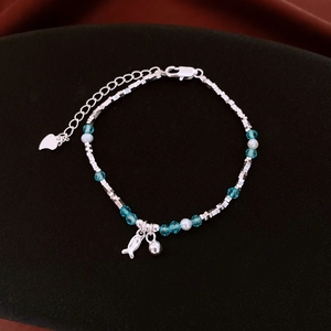 Dettaglio di ciondoli a pesce e cuore in argento su un bracciale di perle blu