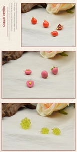 Detailed view of colorful resin fruit pendants including peach and grape with gold loops