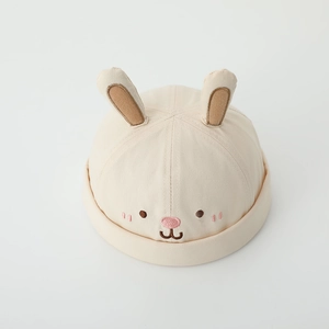 Detail of beige baby brimless cap featuring 3D rabbit ears and cute embroidered face