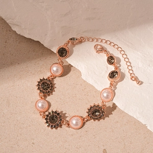 Détail d'un bracelet en or rose avec perles et tournesols sur fond de pierre