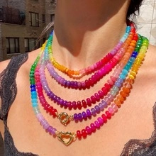 Close-up of multilayered colorful beaded necklace with golden heart charms on a model