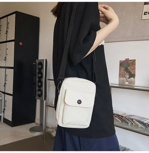 Close-up of white canvas crossbody bag with black buckle strap on male model
