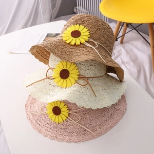 Close-up of three color straw hats showing the woven texture and sunflower decorations