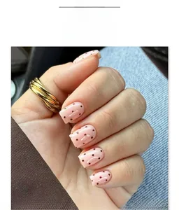 Close-up of short square press-on nails with pink base and dark brown polka dot patterns
