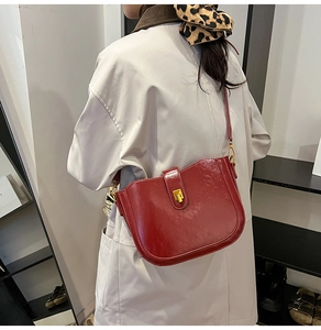 Detail of burgundy leather saddle bag featuring a gold square twist-lock on a model