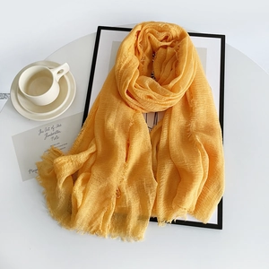 Close-up of yellow linen scarf showing wrinkled fabric texture and raw frayed edges
