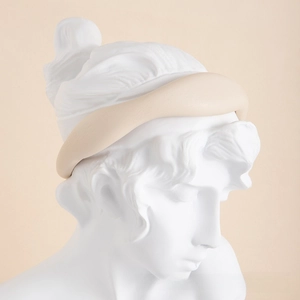 Detail of a thick padded faux leather headband in apricot on a classical statue
