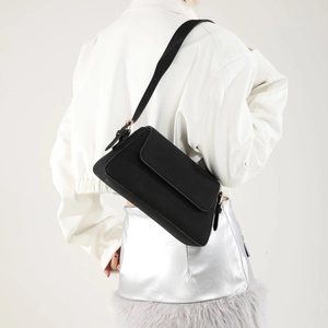 Model wearing a minimalist black PU leather shoulder bag with gold buckles and matte finish