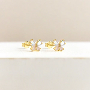 Detailed macro view of S925 sterling silver butterfly studs with pink crystals and gold finish