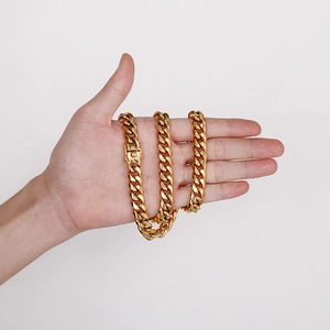 Men's gold Cuban link chain necklace with dragon head clasp shown on hand