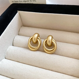 Close-up of matte gold geometric double ring earrings inside a soft fabric jewelry box