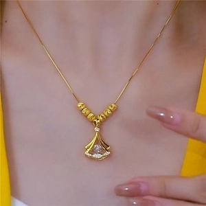 Vue détaillée d'un collier doré avec pendentif en éventail et zircone sur le cou d'un modèle