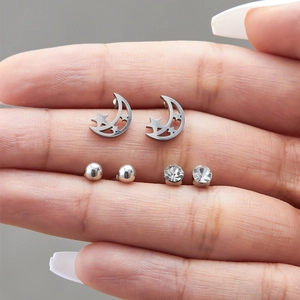 Close-up of three pairs of silver stud earrings including moon, stars and zircon