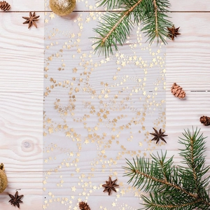 Detail of sheer gold star mesh runner with Christmas pine cones and festive ornaments
