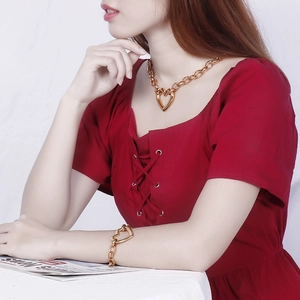 Close-up of gold heart pendant necklace and chunky chain bracelet set worn by a model