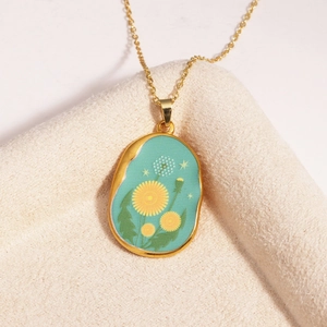 Detailed close-up of a gold vintage necklace with a green dandelion pendant design