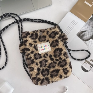 Gros plan d'un sac bandoulière en peluche léopard avec étiquette colorée sur un bureau