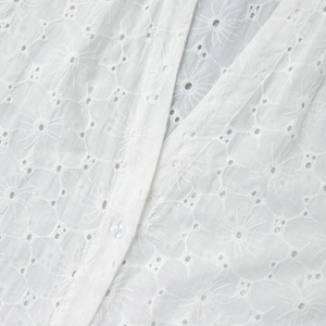 Close-up of white eyelet embroidery dress with single-breasted button and V-neckline detail