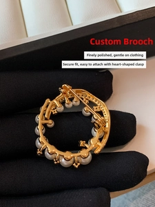Macro view of 24k gold-plated pearl brooch with heart-shaped safety clasp and smooth finish