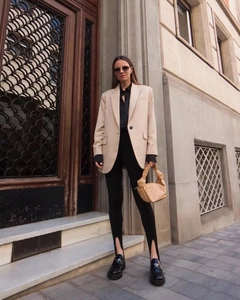 Street style detail of a beige oversized blazer paired with black split hem leggings