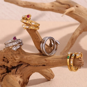 Detail of 18K gold plated heart and arrow rings with zircons on natural wood branch