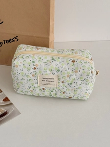 Detail of green floral corduroy makeup bag featuring diamond quilting and zipper closure