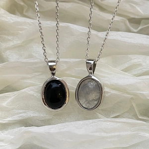 Macro shot of 925 silver necklaces with oval black agate and white moonstone pendants