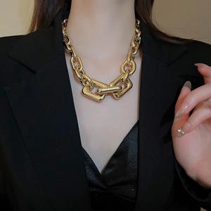 Detailed view of bold gold chunky chain necklace with geometric clasps on a model