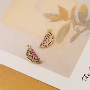 Macro shot of watermelon charms with red and green zircons and hollow gold backings
