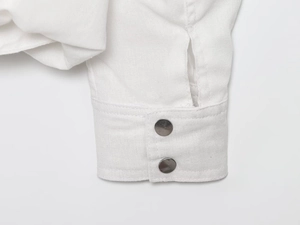 Close-up of white long-sleeve cuff with two silver round metal buttons and woven texture