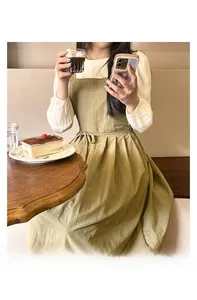 Détail du tablier plissé olive imperméable avec une chemise blanche à manches longues