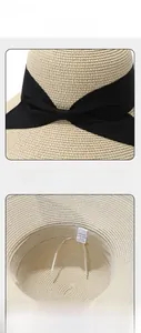 Detail showing the large black ribbon bow and interior sweatband of the paper sun hat