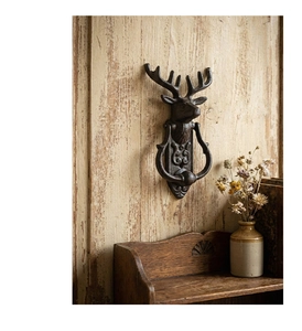 Detailed close-up of a vintage cast iron deer head door knocker on a rustic wooden door