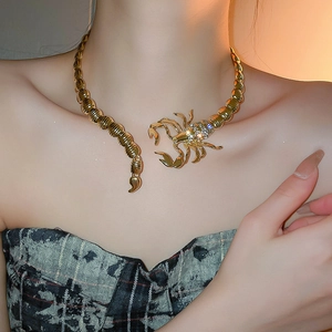 Detailed view of a gold scorpion collar necklace with sparkling rhinestones on a model