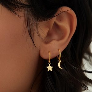 Close-up of gold S925 sterling silver hoop earrings with star and moon charms on model