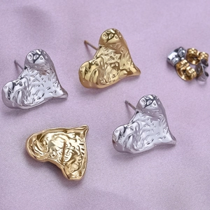 Macro detail of heart-shaped earrings with molten lava texture in gold and silver