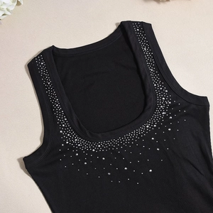 Close-up of sparkling silver rhinestones on a black ribbed knit square neck dress
