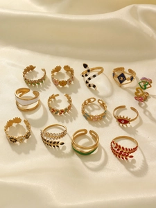 Flat lay of thirteen 18k gold-plated rings with snake and flower enamel patterns on silk