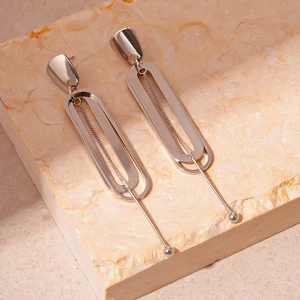 Detail shot of silver double-layer oval geometric earrings on a stone platform