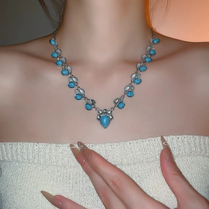 Macro detail of bohemian turquoise waterdrop pendant and silver chain on model neck