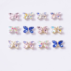 Vue macro de 12 charmes de nail art papillon en cristal multicolore disposés en grille 3x4