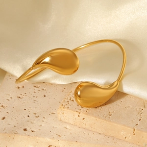 Detail of gold water drop open bangle on stone bases with elegant silk fabric backdrop
