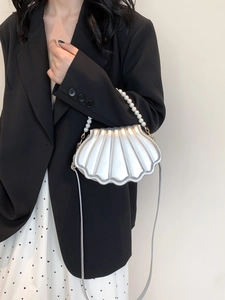 Detail of silver shell-shaped crossbody bag with elegant pearl handle and thin shoulder strap