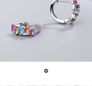 Detailed close-up of silver huggie hoop earrings with five vibrant rainbow gemstones