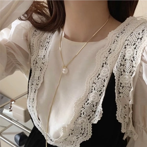 Close-up of elegant gold Y-shaped pearl necklace worn by a model on lace clothing