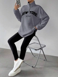 Détail du sweat en polaire grise avec broderie New York et col montant à demi-fermeture